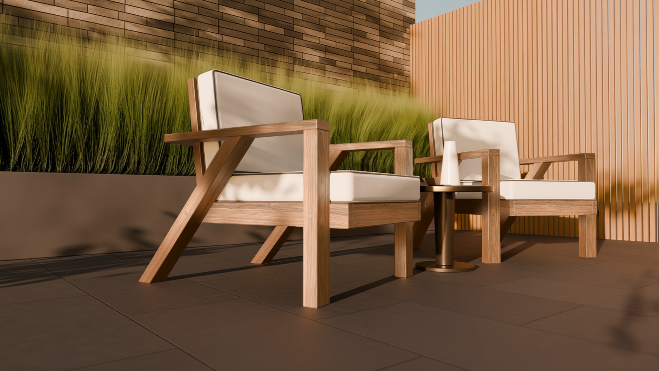 Two teak angled-leg lounge chairs and a bronze side table on a patio in low golden light, leaf shadows across the pavers