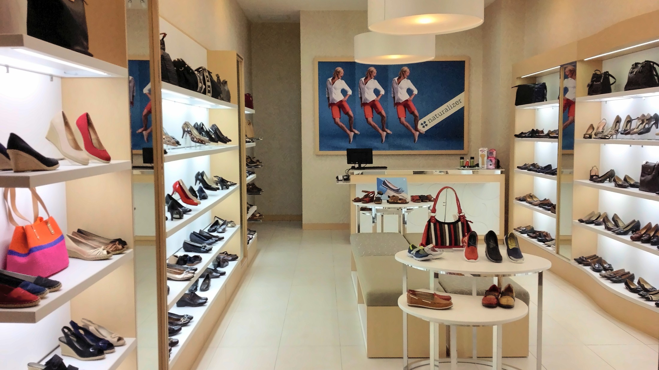 The full Naturalizer store in Miraflores, Lima: lit wall shelving, display tables and the brand panel