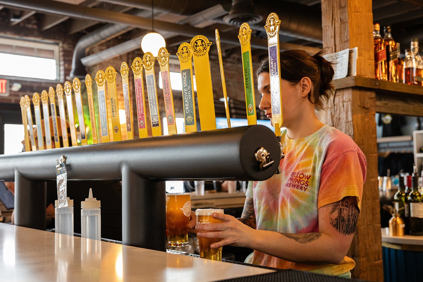 A bartender pours under a row of yellow tap handles