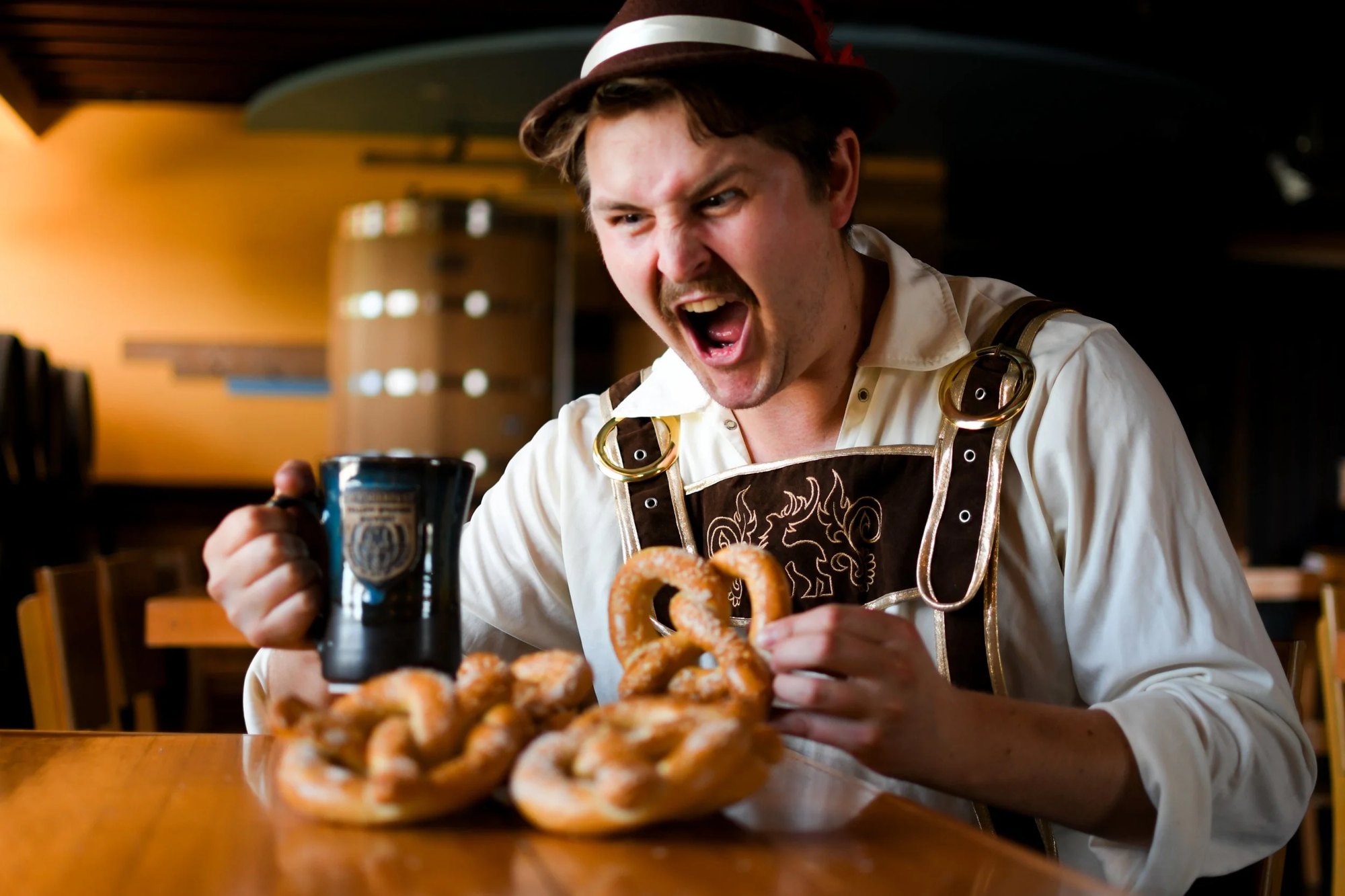 Emcee Elliot Cromer in lederhosen with a stein and pretzels
