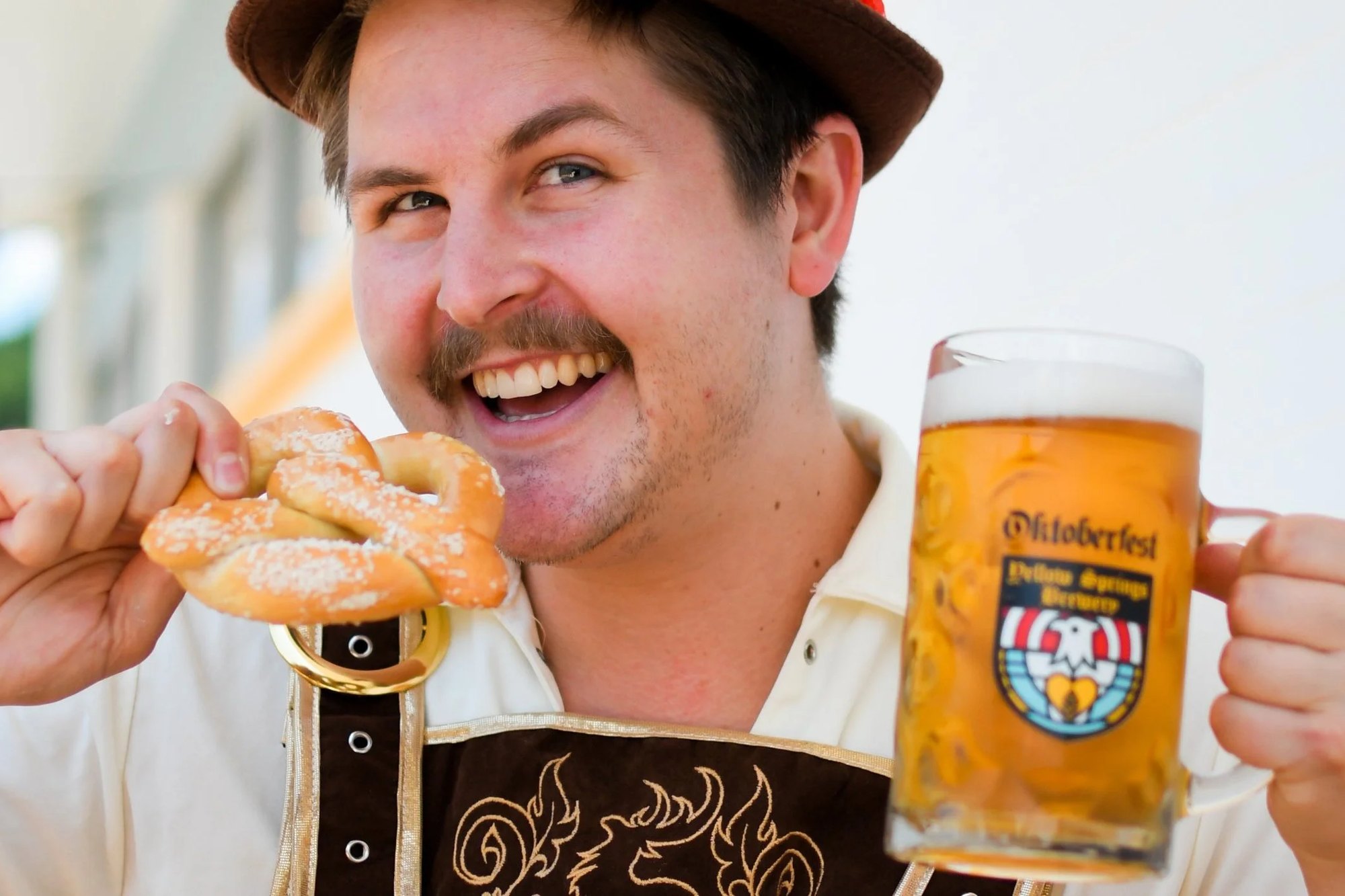Elliot Cromer grins with a pretzel and an Oktoberfest stein