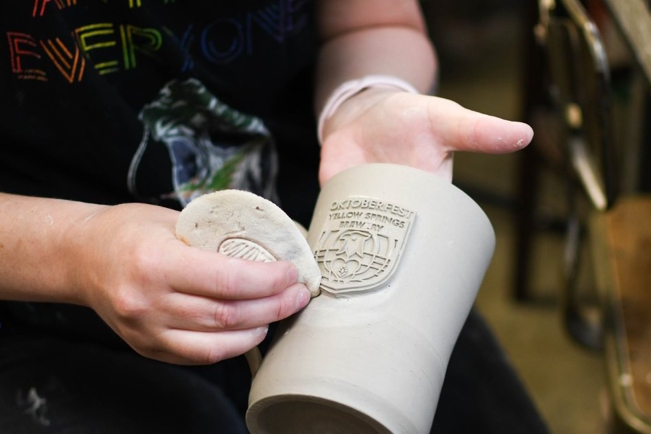 Meg Smallwood holds a freshly thrown stein stamped with the brewery logo